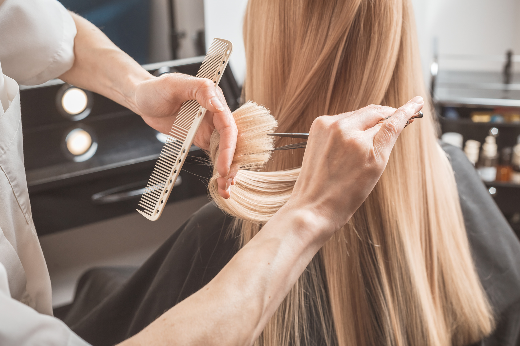hairdresser is cutting long hair in hair salon
